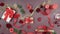 Festive table background with rose petals, burning candles, gifts, red ribbon and little hearts. Extinguished red aroma candles on