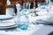 Festive table set, catering with white cloth, plates, forks, blue glasses, salt and pepper pots for wedding, family event or party