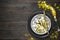 Festive table setting with black dish, clock, wine glass and gold confetti decoration on dark wooden table