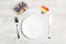 Festive table setting with cutlery and gift with rainbow LGBT ribbon on a light wooden background