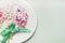 Festive table setting with spring flowers , plate and ribbon on light pastel wooden background, top view