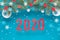 Festive winter background with fir twigs, blue red and white paper decorations and number 2020