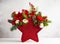 Festive winter flower arrangement in vase of red star shape. Christmas flower composition for holiday