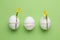 Festively Easter eggs decorated with flowers on green background, flat lay