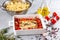 Feta cheese pasta sauce recipe step. Tomatoes drizzled with olive oil in a baking dish with a feta cheese block in the middle and