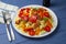 Fettuccine with grilled meat, carrots, bell peppers, dill tomatoes on a blue wooden background. Pasta with vegetables.