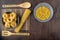 Fettuccine pasta in a grey plate on a bamboo napkin and spaghetti, a bowl of pasta and bamboo spatulas on a wooden background