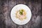 Fettuccine pasta with meat, cream sauce and herbs on a plate on wooden background