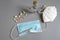 Fever thermometer with over blue surgical mask on gray background with others white KN95 masks and medicines pills