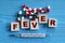 FEVER - word on wooden cubes on a blue background with tablets and thermometer