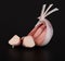 A few cloves of young fresh garlic in a transparent husk, a cut clove of garlic on a black background with a reflection.