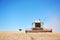 A few combines cutting a swath through the middle of a wheat field during harvest