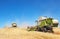 A few combines cutting a swath through the middle of a wheat field during harvest