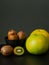 Few kiwi in black plate and sweetie still life on dark background.