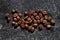 Few quality roasted coffee beans at dark marble sufface. High quality coffee beans detail. View from above