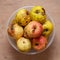 A few red-yellow overripe apples in a round bowl