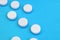 A few white tablets lie on a bright blue background surface. Background image on medical and pharmaceutical topics