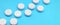 A few white tablets lie on a bright blue background surface. Background image on medical and pharmaceutical topics