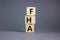 FHA symbol. Wooden cubes form the word `FHA, federal housing administration`. Beautiful grey background, copy space. Business an