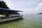 Fiber boat anchored near the shore, cloudy sky background.