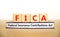 FICA symbol. Concept words FICA federal insurance contributions act on wooden block on beautiful white background. Business FICA