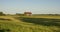 A field with a barn and a big tree shawow.