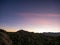 Field of boulders at dusk with sunset sky and crescent moon in Yucca Valley California near Joshua Tree National Park