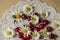 Field daisies and red cherries on an openwork white paper napkin on a wooden table