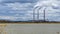 The field with the died and dried-up flowers against the background of large oil refinery. Dramatic sky background