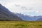 Field and distant snowy mountains. South Island landscapes. Fiordland National Park. New Zealand