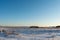 The field with dry grass is covered with snow. Large shadows from hilly snow. Winter landscape in the evening with clear blue sky