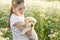 In a field with flowers, a girl lovingly holds her Labrador puppy tightly in her arms