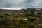 field with grass and stones with houses under stormy sky, Norway, Hardangervidda