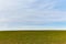 Field with green grass horizon blue sky