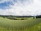 Field of growing wheat with beautiful view on landscape of Dolomites moutains in the clouds with small houses in valley