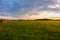 A field with haystacks is illuminated by the sun.