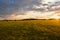 A field with haystacks is illuminated by the sun.