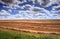 Field with hewed corn and clouds