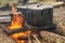 Field kitchen. Saucepan, pot and kettle on fire from the bonfire. Water boils and cooking food in the tourist camp