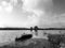 Field landscape flooded by rainwater, with cloudy sky, in black and white