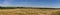 A field of ripe wheat at the foot of a small mountain. Panoramic shot of a field.