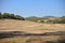 Field with shadows of trees and old castle on a hill under blue sky