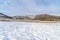 Field with snow in winter with homes on snowy hill against sky backgdrop