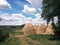 Field with straw haystacks, rural landscape on cloudy sky background