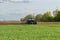 On the field, the tractor plows the ground.