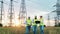 Field with transmission towers with engineers walking along it