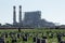 Field Worker Picking Produce in Front of Power Plant