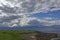 Fields running down to the shingle and rocky beach at John Oâ€™Groats with scattered houses and farm Buildings.