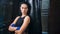 Fierce young Asian female kickboxer posing near punching bag looking at camera medium shot