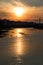 Fiery sunset over the calmly flowing Ural river and pedestrian bridge